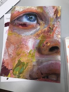 an art project is being displayed on a table with paint and paper, including one blue eye