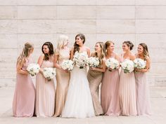 a group of women standing next to each other wearing dresses and holding bouquets in their hands