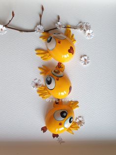 three yellow fish figurines sitting on top of a white wall next to flowers