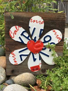 a wooden sign that has been decorated with red, white and blue flowers