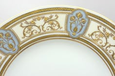 an ornately decorated plate with gold and blue decorations on the rim, against a white background