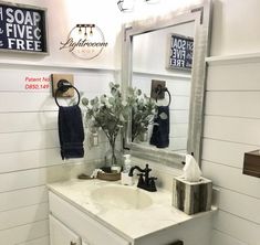 a white bathroom sink sitting under a mirror next to a wooden shelf with towels on it