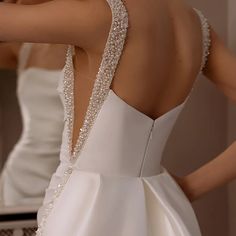 the back of a woman's wedding dress in front of a mirror with her hand on her shoulder