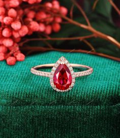 a close up of a ring with a red stone in the center on a green cloth