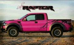 a pink pick up truck parked on top of a dry grass covered field with the word raptor written above it