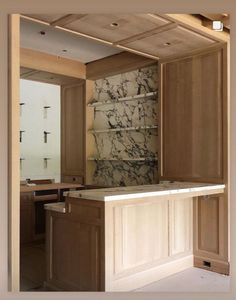 an empty kitchen with marble counter tops and cabinets in the middle, looking into the dining room