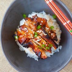 two plates filled with food and chopsticks on top of rice covered in sauce