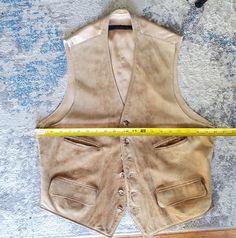 Men's Brooks Brothers leather/suede vest in a tan color with a satin fabric lining. Vintage worn condition with discolorations, scuffs, and signs of age. This is a unmarked size. Please check measurements. Total length from top to bottom is approximately 25" Armpit to armpit is approximately 20" across Rugged Fitted Vest Outerwear, Fitted Sleeveless Rugged Outerwear, Fitted Leather Vest With Rugged Style, Fitted Leather Vest In Rugged Style, Fitted Rugged Brown Vest, Fitted Brown Rugged Vest, Brown Sleeveless Vest For Western-themed Events, Fitted Western Vest Outerwear, Fitted Western Style Vest Outerwear