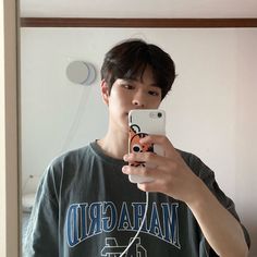 a young man taking a selfie in front of a mirror with his cell phone