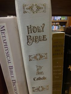 three books are stacked on top of each other in front of a book shelf filled with books