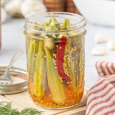 pickled vegetables sit in a jar on a cutting board