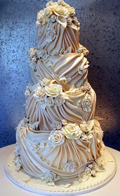 a three tiered wedding cake with white flowers on it's side and blue background