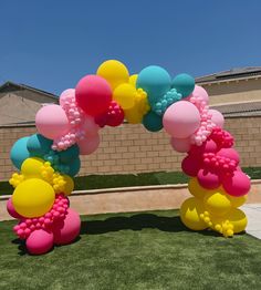 an arch made out of balloons in the shape of flowers and hearts on fake grass