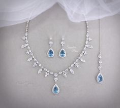 the bride's necklace and earrings are adorned with swarong crystal leaves, which also include pear shaped blue topazts