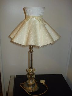 a lamp that is on top of a table with a white dress on it's side