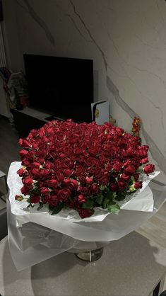 a bouquet of red roses sitting on top of a white table next to a tv