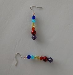 two pairs of colorful beaded earrings sitting on top of a white table next to each other