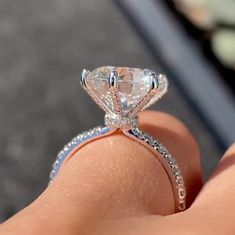 a close up of a person's hand holding a diamond ring