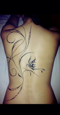 the back of a woman's body with an artistic tattoo design on her stomach