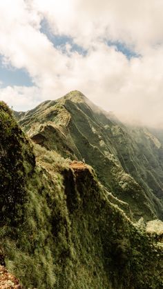 the mountains are covered in green vegetation and clouds