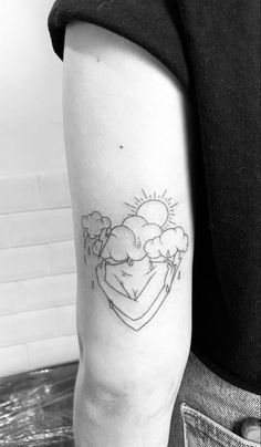 a black and white photo of a woman's arm with clouds, sun and hearts