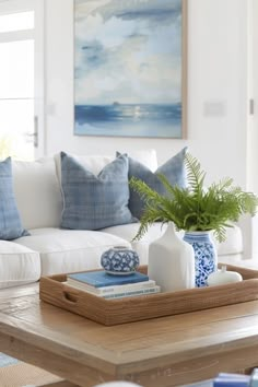 a living room with white couches and blue and white decor on the coffee table