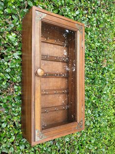 an old wooden box with water spouting out of it's sides in front of a green hedge