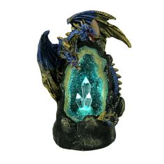 a blue and green dragon figurine sitting on top of a rock