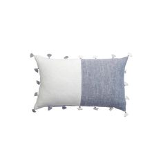 a blue and white pillow with pom poms on the bottom, in front of a