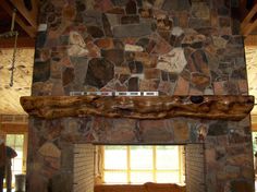 a stone fireplace in a living room with wood trimmings on the mantel