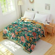 a bed covered in a green floral comforter next to a night stand and window