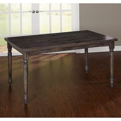 a wooden table sitting on top of a hard wood floor next to an open window