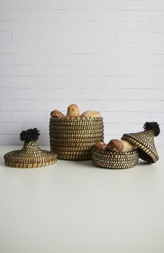 three baskets filled with bread sitting on top of a white table next to a brick wall