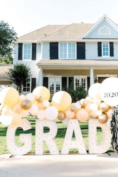 a large sign that says grad in front of a house with balloons on it