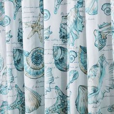 shower curtain with shells and starfishs printed on it's side, hanging in front of a window