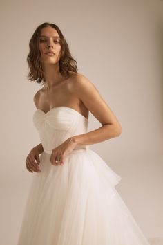 a woman in a white dress posing for the camera with her hands on her hips