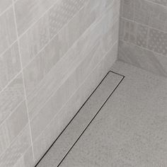 the corner of a shower stall in a bathroom with gray tiles on the walls and floor