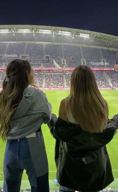 two women standing in front of an empty stadium