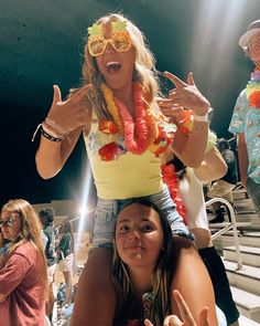 a woman sitting on the back of another woman at a baseball game with her hands in the air