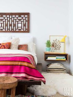 a bed room with a neatly made bed next to a wooden table and shelf filled with books