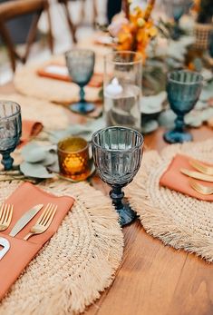 the table is set with silverware and orange napkins