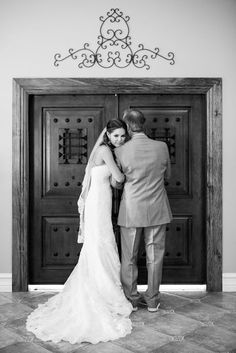 a bride and groom standing in front of a door