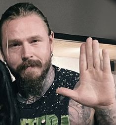 a man with long hair and piercings holding his hand up in front of him