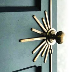 a door handle on a green door with gold accents and sunburst design in the center