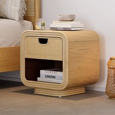 a nightstand with books on it next to a bed