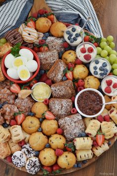 a platter filled with fruit, pastries and desserts on top of a wooden table