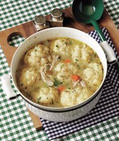 a white bowl filled with dumplings on top of a checkered table cloth next to a spoon