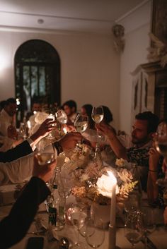 a group of people toasting wine glasses at a dinner table