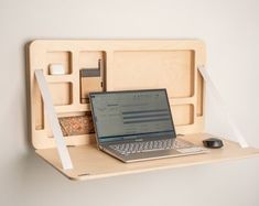 an open laptop computer sitting on top of a wooden shelf