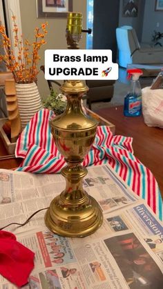 a brass lamp on top of a newspaper with red and white striped ribbon around it